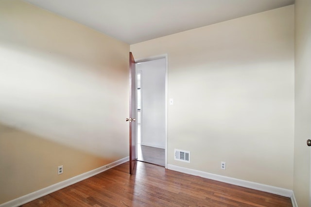 empty room with baseboards, visible vents, and wood finished floors
