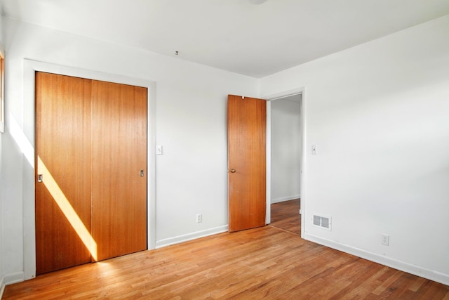 unfurnished bedroom with baseboards, visible vents, and wood finished floors