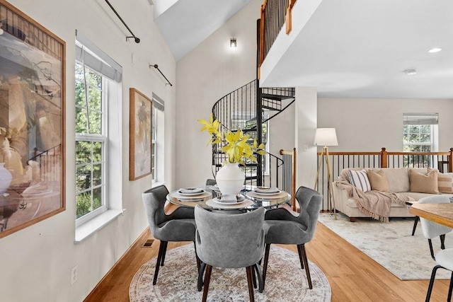 dining area featuring stairway, a high ceiling, wood finished floors, and visible vents