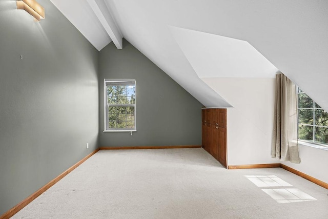 bonus room featuring plenty of natural light, lofted ceiling with beams, and baseboards