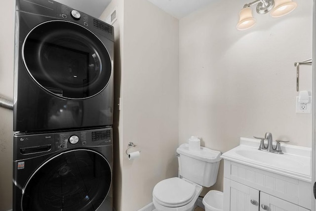 bathroom with toilet, baseboards, stacked washer / dryer, and vanity