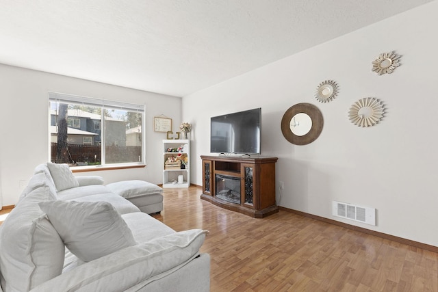 3713 S Harrison St, Spokane, WA 99224 - living area with a glass covered fireplace, baseboards, wood finished floors, and visible vents