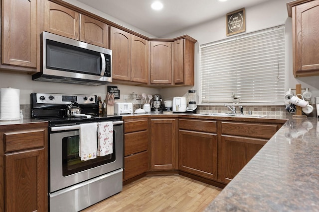 3713 S Harrison St, Spokane, WA 99224 - kitchen featuring appliances with stainless steel finishes, dark countertops, brown cabinets, a sink, and light wood-style flooring
