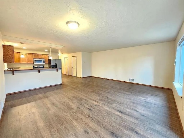 3713 S Harrison St, Spokane, WA 99224 - unfurnished living room with visible vents, baseboards, a textured ceiling, and wood finished floors
