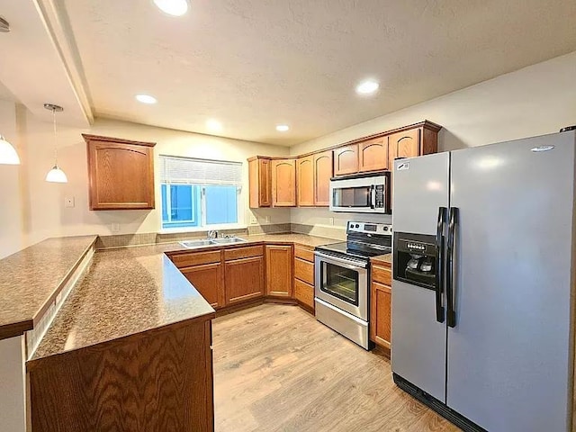 3713 S Harrison St, Spokane, WA 99224 - kitchen featuring appliances with stainless steel finishes, a sink, light wood finished floors, a peninsula, and pendant lighting