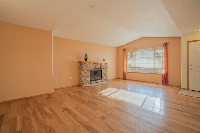 unfurnished living room featuring baseboards, a fireplace, vaulted ceiling, and wood finished floors