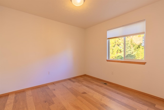 unfurnished room featuring baseboards, light wood finished floors, and visible vents