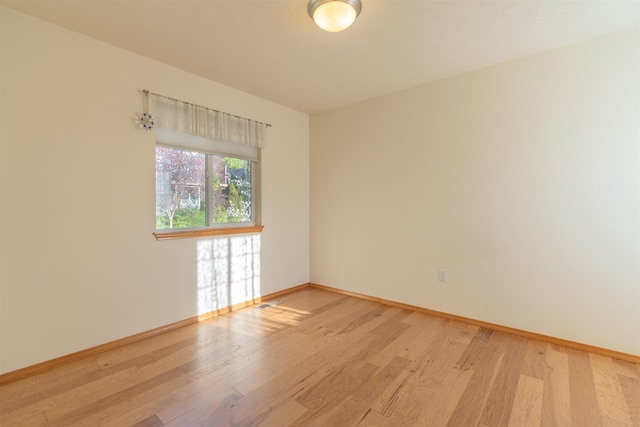 unfurnished room featuring baseboards and light wood finished floors