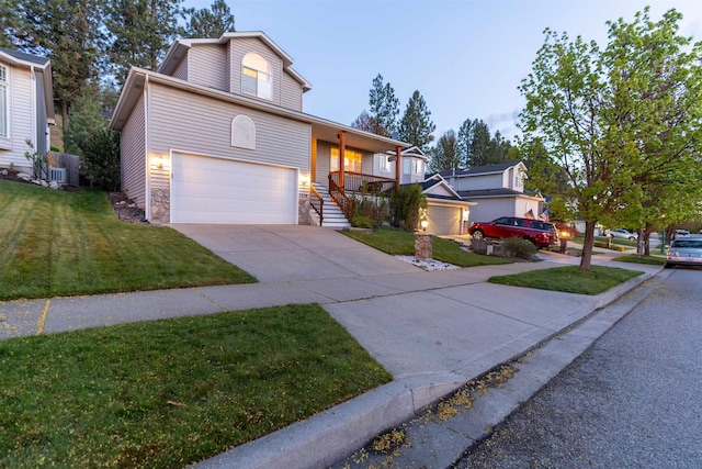 traditional-style home featuring an attached garage, driveway, a front lawn, and stone siding
