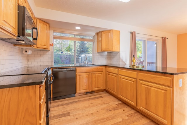 kitchen featuring tasteful backsplash, a sink, black appliances, light wood finished floors, and a peninsula