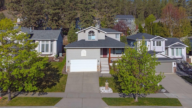 traditional-style home featuring covered porch, driveway, a residential view, a garage, and stairway