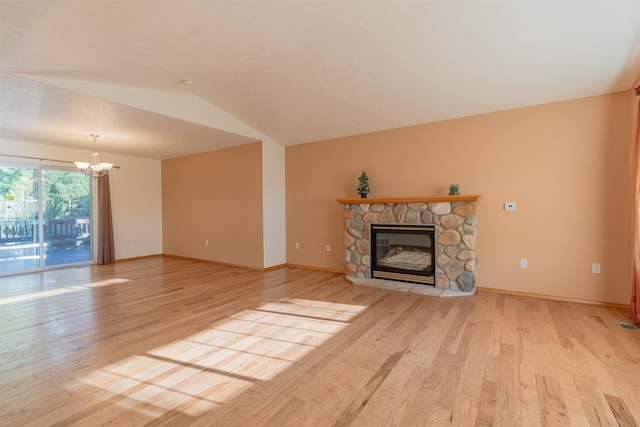 unfurnished living room with light wood-style flooring, a fireplace, a notable chandelier, and vaulted ceiling