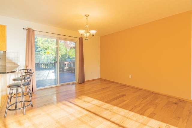 empty room with a notable chandelier and light wood-style flooring
