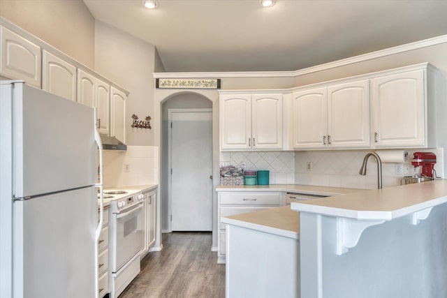 6805 Royal Ln, Spokane, WA 99208 - kitchen with white appliances, a peninsula, a breakfast bar, tasteful backsplash, and white cabinetry