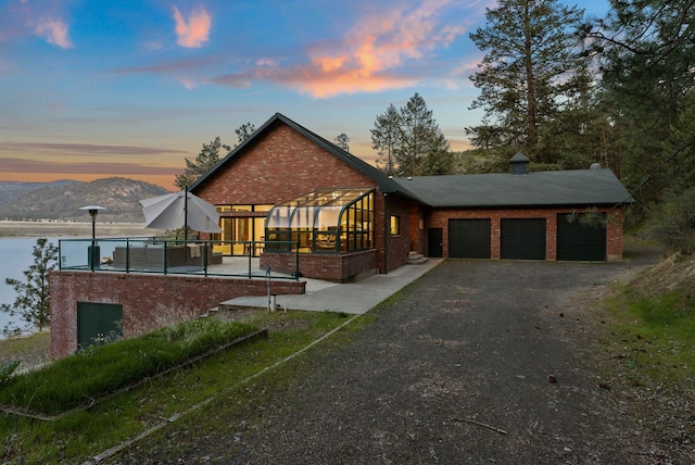 chalet / cabin featuring brick siding, an attached garage, driveway, and a mountain view