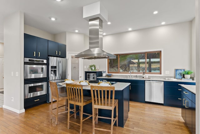 kitchen featuring a breakfast bar area, a kitchen island, blue cabinets, island exhaust hood, and stainless steel appliances