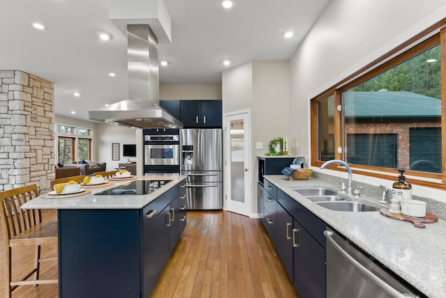 kitchen with a kitchen island, island exhaust hood, a sink, appliances with stainless steel finishes, and blue cabinetry