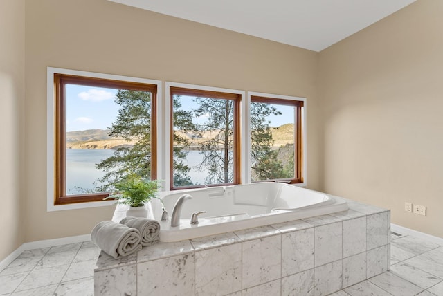 bathroom with baseboards, a garden tub, and marble finish floor