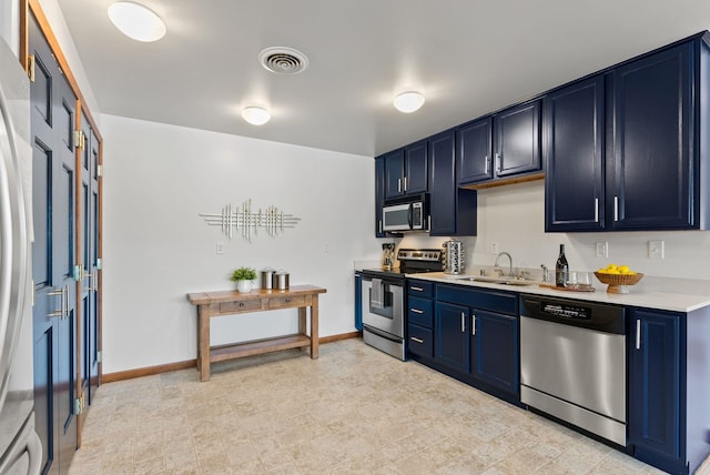 kitchen featuring light countertops, stainless steel appliances, blue cabinetry, and a sink