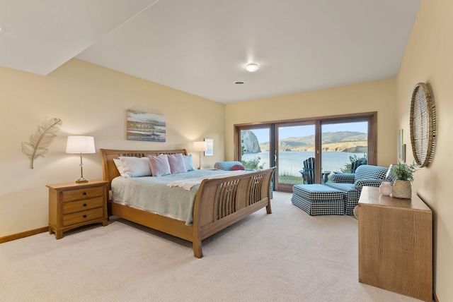 bedroom featuring a water view, baseboards, light carpet, and access to exterior