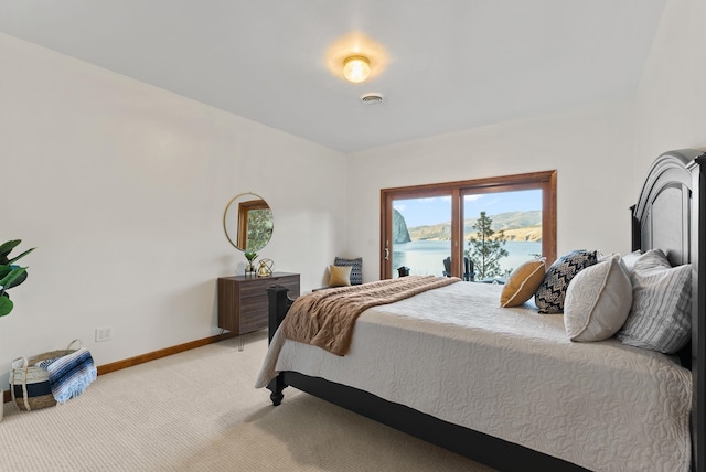 bedroom featuring baseboards, access to outside, light carpet, and a water view