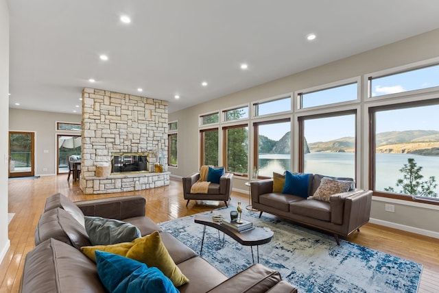 living area featuring baseboards, a fireplace, recessed lighting, and light wood-style flooring
