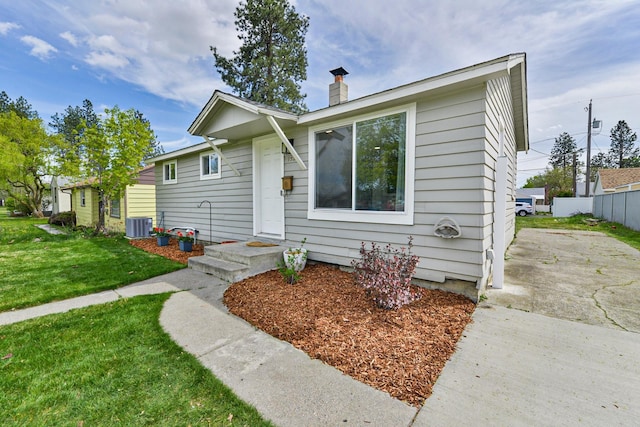 ranch-style house featuring central AC unit, a front lawn, fence, and a chimney