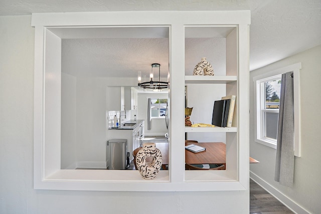 details featuring a sink, baseboards, wood finished floors, and a chandelier