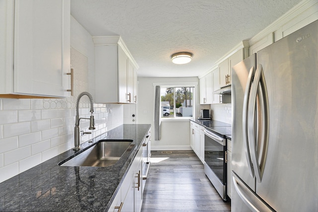 kitchen with backsplash, a sink, dark wood-style floors, stainless steel appliances, and white cabinetry