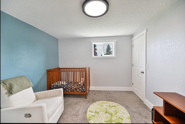 bedroom with carpet flooring, a nursery area, a textured ceiling, and baseboards