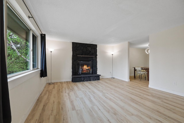 unfurnished living room featuring a textured ceiling, wood finished floors, a healthy amount of sunlight, and a fireplace