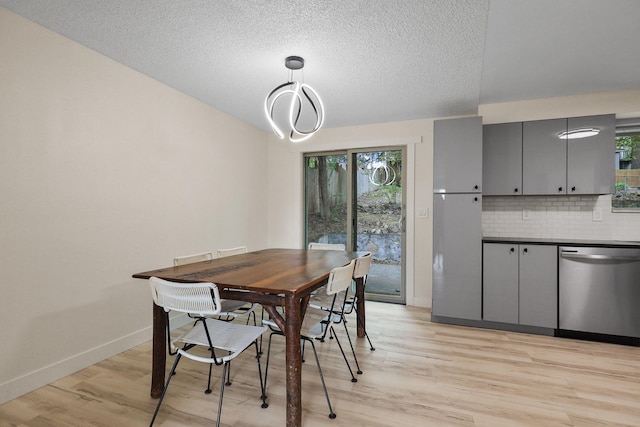 dining area with baseboards, a textured ceiling, light wood-style flooring, and a wealth of natural light