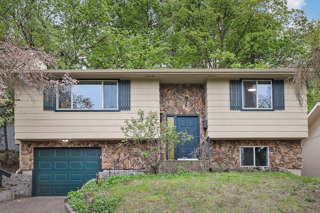 split foyer home with a garage, driveway, and stone siding