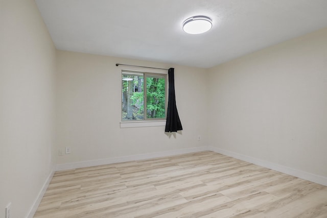spare room featuring baseboards and wood finished floors