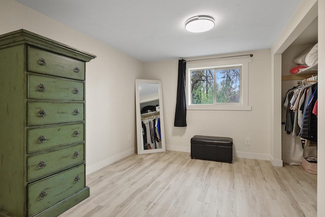 bedroom with baseboards, light wood-style flooring, and a closet
