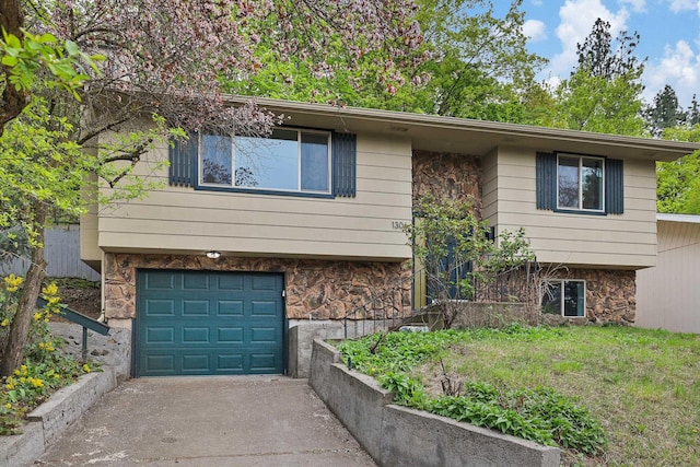 bi-level home featuring a garage, driveway, and stone siding