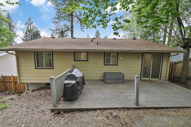 rear view of property with roof with shingles, fence, and a deck