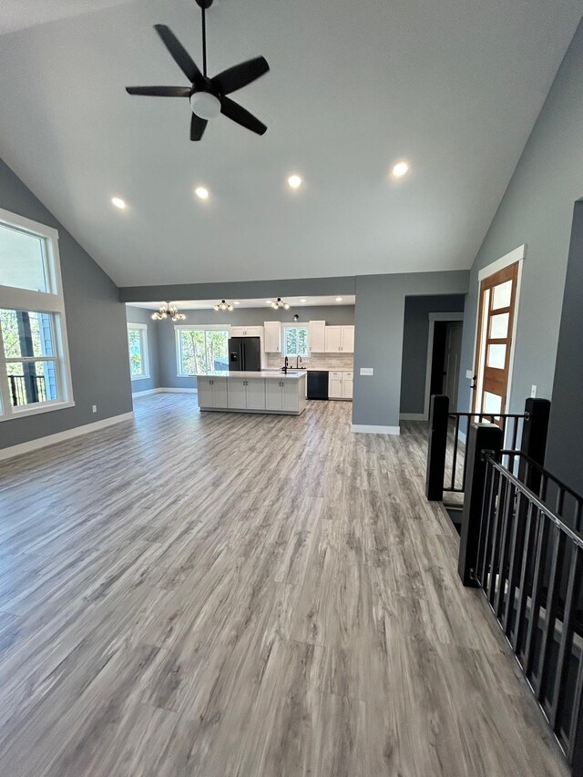 unfurnished living room featuring recessed lighting, baseboards, vaulted ceiling, and ceiling fan with notable chandelier