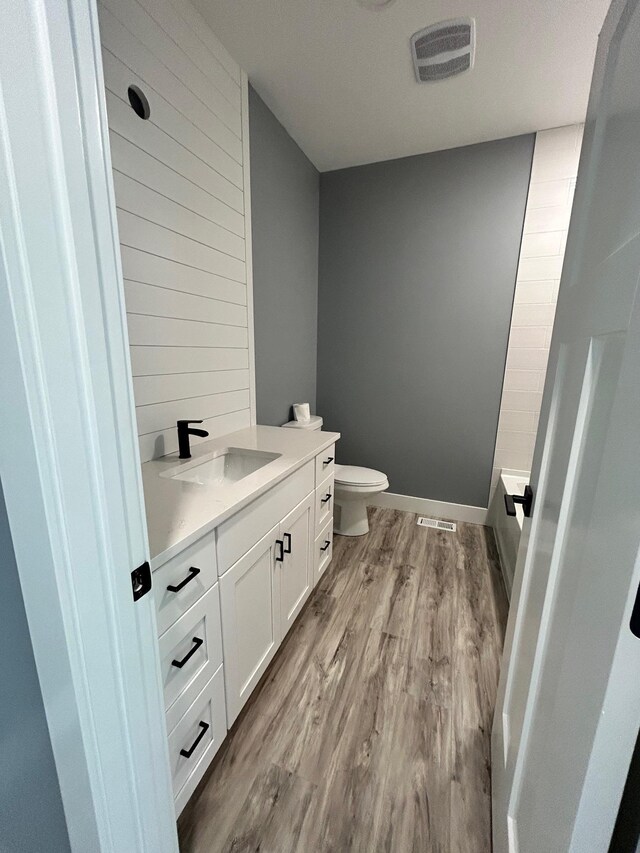 full bath with visible vents, wood finished floors, toilet, and vanity