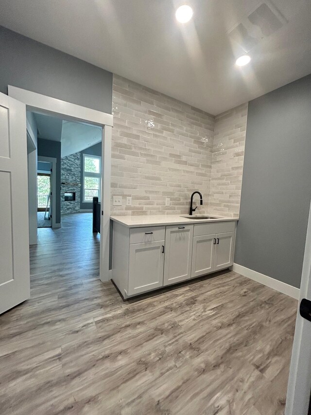 bar featuring a sink, baseboards, and light wood-style flooring