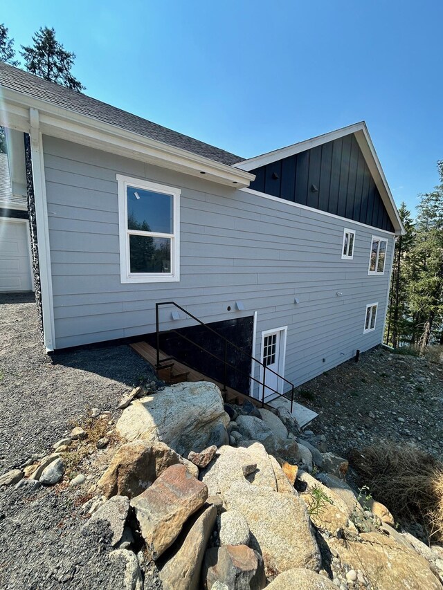 back of house with board and batten siding and a shingled roof