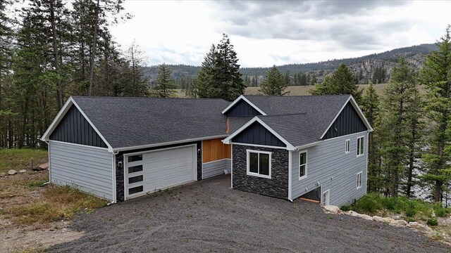 craftsman-style home featuring a garage, board and batten siding, driveway, and a forest view