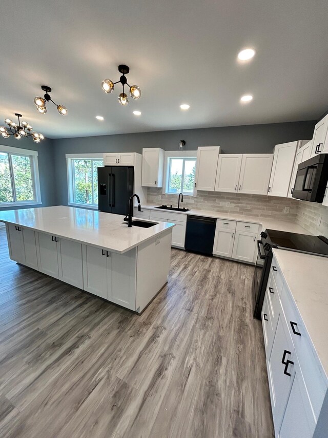 kitchen featuring an inviting chandelier, a sink, black appliances, and a wealth of natural light