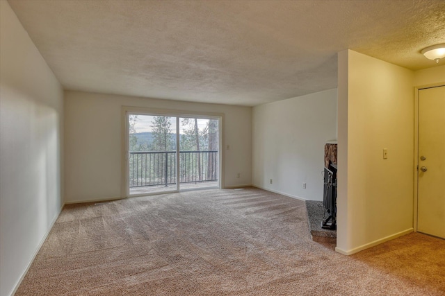 2514 E Casper Dr, Spokane, WA 99223 - unfurnished room featuring baseboards, a fireplace with raised hearth, a textured ceiling, and light carpet