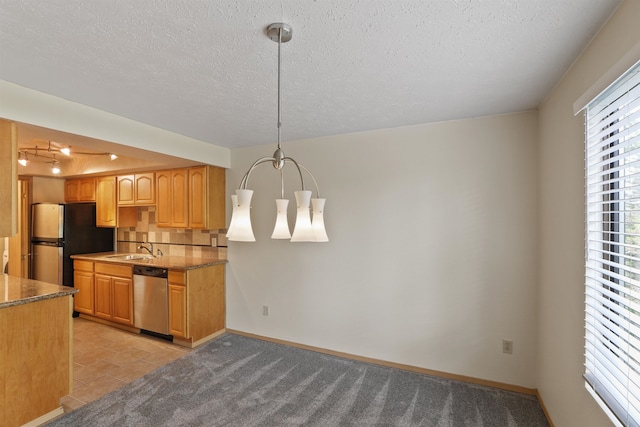 kitchen featuring a textured ceiling, pendant lighting, tasteful backsplash, a sink, and stainless steel appliances