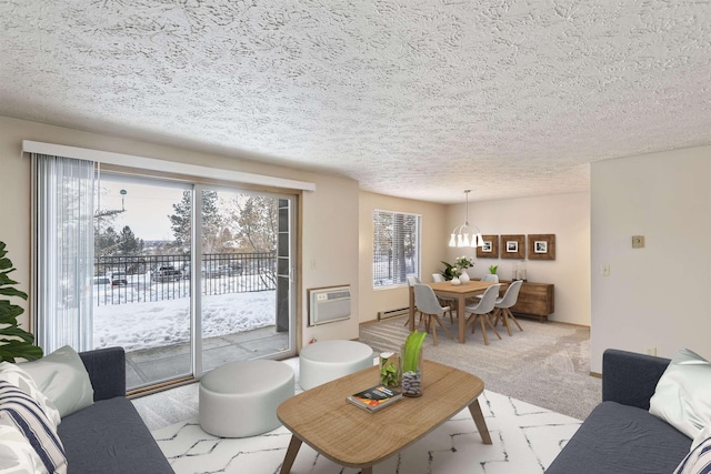 living room with an AC wall unit, a textured ceiling, a baseboard heating unit, and light carpet