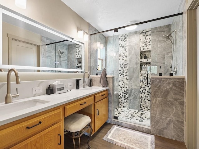 full bath featuring double vanity, a sink, wood finished floors, and a shower stall