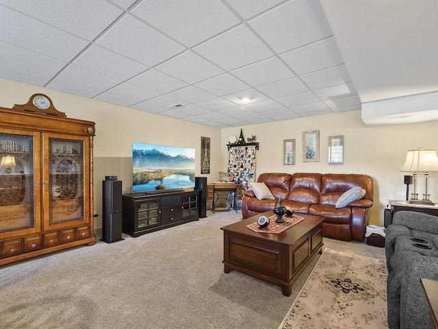 carpeted living area featuring a drop ceiling