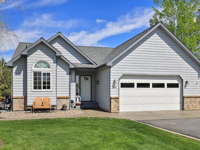 ranch-style house featuring roof with shingles, a front yard, driveway, and brick siding