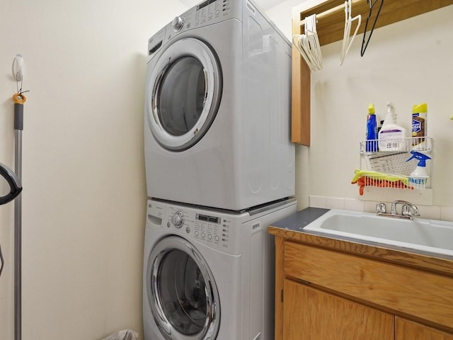 laundry room featuring a sink, stacked washer and dryer, and cabinet space